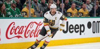 Vegas Golden Knights captain Mark Stone in white jersey skating with the puck during an NHL game, amid speculation regarding his injury history and potential retirement.