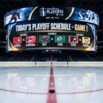 Jumbotron over center ice in an empty hockey arena, displaying the game schedule and team matchups for the first day of the 2026 NHL Playoffs, a critical piece of NHL news.