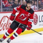 New Jersey Devils captain Nico Hischier skating on the ice, facing NHL trade rumors linking him to the Minnesota Wild and Ottawa Senators.