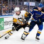 Pittsburgh Penguins captain Sidney Crosby (87) battles St. Louis Blues center Robert Thomas (18) for the puck along the boards at Enterprise Center during an NHL game, highlighting how to watch these teams clash on TV.