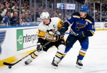 Pittsburgh Penguins captain Sidney Crosby (87) battles St. Louis Blues center Robert Thomas (18) for the puck along the boards at Enterprise Center during an NHL game, highlighting how to watch these teams clash on TV.