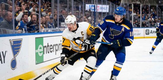 Pittsburgh Penguins captain Sidney Crosby (87) battles St. Louis Blues center Robert Thomas (18) for the puck along the boards at Enterprise Center during an NHL game, highlighting how to watch these teams clash on TV.