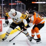Pittsburgh Penguins center Evgeni Malkin (71) battles Philadelphia Flyers forward Travis Konecny (11) along the boards for puck possession during an intense NHL playoff game in the Battle of Pennsylvania rivalry.