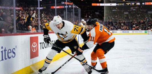 Pittsburgh Penguins center Evgeni Malkin (71) battles Philadelphia Flyers forward Travis Konecny (11) along the boards for puck possession during an intense NHL playoff game in the Battle of Pennsylvania rivalry.