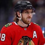 Concept image of Robert Thomas wearing a red Chicago Blackhawks jersey amidst NHL trade rumors involving a blockbuster deal with the St. Louis Blues.