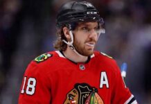 Concept image of Robert Thomas wearing a red Chicago Blackhawks jersey amidst NHL trade rumors involving a blockbuster deal with the St. Louis Blues.