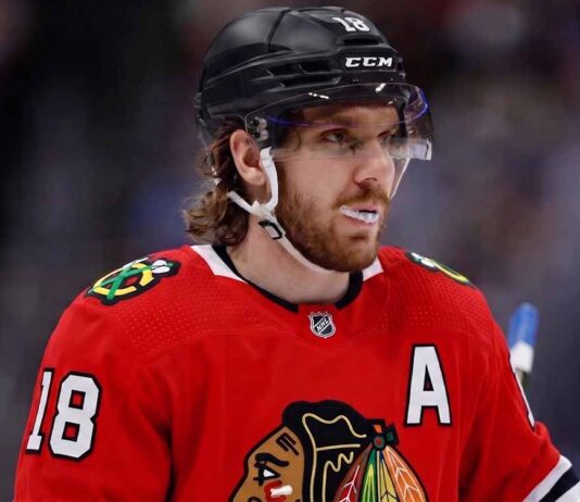 Concept image of Robert Thomas wearing a red Chicago Blackhawks jersey amidst NHL trade rumors involving a blockbuster deal with the St. Louis Blues.