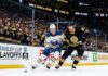 A dynamic photo of Buffalo Sabres and Boston Bruins players battling on the ice during Game 3 of the Stanley Cup Playoffs at TD Garden on April 23, 2026.