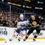 A dynamic photo of Buffalo Sabres and Boston Bruins players battling on the ice during Game 3 of the Stanley Cup Playoffs at TD Garden on April 23, 2026.