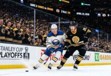 A dynamic photo of Buffalo Sabres and Boston Bruins players battling on the ice during Game 3 of the Stanley Cup Playoffs at TD Garden on April 23, 2026.