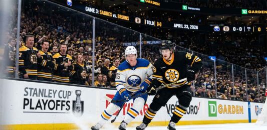 A dynamic photo of Buffalo Sabres and Boston Bruins players battling on the ice during Game 3 of the Stanley Cup Playoffs at TD Garden on April 23, 2026.