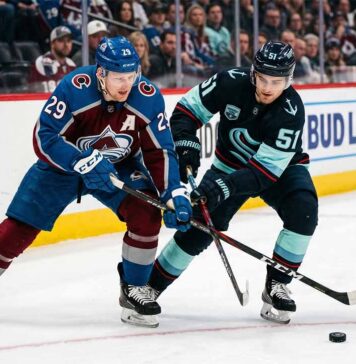 Nathan MacKinnon and Shane Wright clashing sticks during a puck battle at Ball Arena.