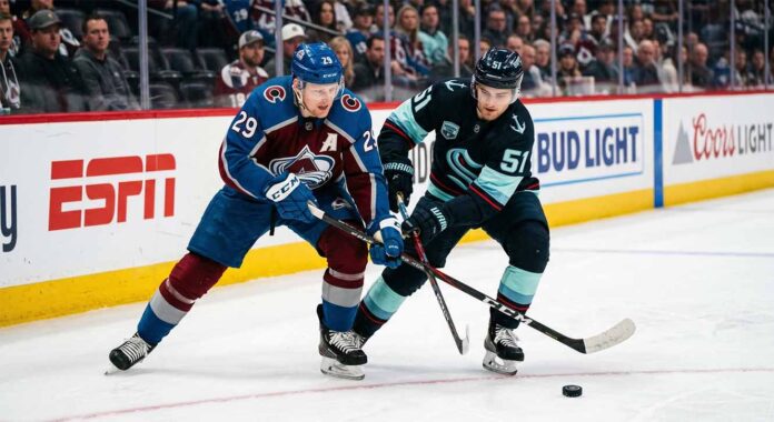 Nathan MacKinnon and Shane Wright clashing sticks during a puck battle at Ball Arena.