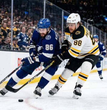 Tampa Bay Lightning's Nikita Kucherov (86) and Boston Bruins' David Pastrnak (88) battle for puck possession along the boards during an intense Atlantic Division NHL game.
