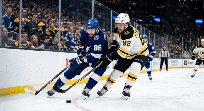 Tampa Bay Lightning's Nikita Kucherov (86) and Boston Bruins' David Pastrnak (88) battle for puck possession along the boards during an intense Atlantic Division NHL game.
