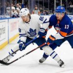 Action shot of Toronto Maple Leafs forward William Nylander battling New York Islanders center Mathew Barzal for the puck during an NHL regular season game.