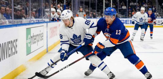 Action shot of Toronto Maple Leafs forward William Nylander battling New York Islanders center Mathew Barzal for the puck during an NHL regular season game.