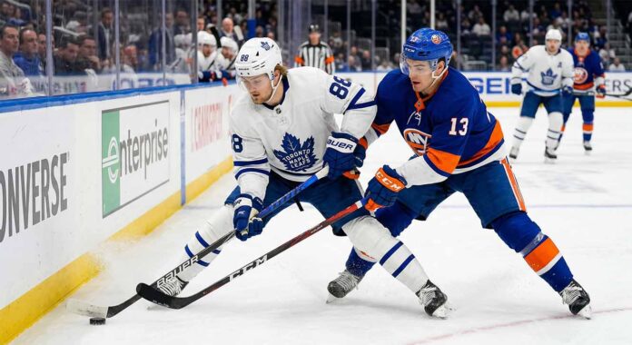 toronto-maple-leafs-new-york-islanders-april-2026-game Action shot of Toronto Maple Leafs forward William Nylander battling New York Islanders center Mathew Barzal for the puck during an NHL regular season game.
