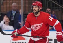 A conceptual image showing New York Rangers center Vincent Trocheck wearing a Detroit Red Wings home jersey #16 on the ice, illustrating NHL trade rumors.