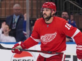 A conceptual image showing New York Rangers center Vincent Trocheck wearing a Detroit Red Wings home jersey #16 on the ice, illustrating NHL trade rumors.