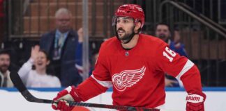 A conceptual image showing New York Rangers center Vincent Trocheck wearing a Detroit Red Wings home jersey #16 on the ice, illustrating NHL trade rumors.