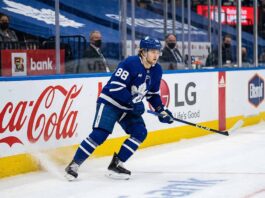 William Nylander (#88) of the Toronto Maple Leafs, in dynamic action on the ice, skating along the arena boards with visible advertising for Coca-Cola and LG, during an NHL game.