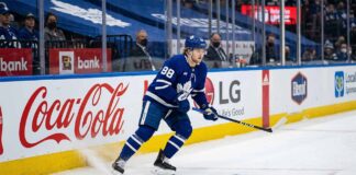 William Nylander (#88) of the Toronto Maple Leafs, in dynamic action on the ice, skating along the arena boards with visible advertising for Coca-Cola and LG, during an NHL game.