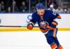 New York Islanders Interest in Simon Nemec | Devils Trade Rumors A photorealistic depiction of New Jersey Devils defenseman Šimon Nemec wearing a New York Islanders home uniform, illustrating trade rumors linking the player to the Islanders.