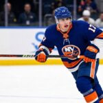 New York Islanders Interest in Simon Nemec | Devils Trade Rumors A photorealistic depiction of New Jersey Devils defenseman Šimon Nemec wearing a New York Islanders home uniform, illustrating trade rumors linking the player to the Islanders.