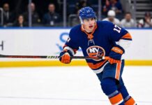 New York Islanders Interest in Simon Nemec | Devils Trade Rumors A photorealistic depiction of New Jersey Devils defenseman Šimon Nemec wearing a New York Islanders home uniform, illustrating trade rumors linking the player to the Islanders.