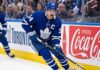 Toronto Maple Leafs captain Auston Matthews controls the puck during an NHL game against a background with Coca-Cola advertising.