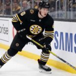 Boston Bruins Trade Rumors: Will Mason Lohrei Be Traded for a Top-Six Forward? Boston Bruins defenseman Mason Lohrei looks to advance the puck during a game. Lohrei, wearing jersey number 6, is the subject of recent NHL trade rumors suggesting he could be moved for a top-six forward.
