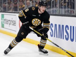 Boston Bruins Trade Rumors: Will Mason Lohrei Be Traded for a Top-Six Forward? Boston Bruins defenseman Mason Lohrei looks to advance the puck during a game. Lohrei, wearing jersey number 6, is the subject of recent NHL trade rumors suggesting he could be moved for a top-six forward.