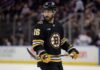Conceptual photo of New York Rangers center Vincent Trocheck wearing a black Boston Bruins home jersey, number 16, holding a hockey stick on the ice.