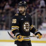 Conceptual photo of New York Rangers center Vincent Trocheck wearing a black Boston Bruins home jersey, number 16, holding a hockey stick on the ice.