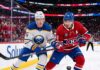 An intense moment on the ice during the Buffalo Sabres and Montreal Canadiens Game 6 matchup as Sabres defenseman Rasmus Dahlin (#26) and Canadiens captain Nick Suzuki (#14) battle fiercely for the puck at Centre Bell.