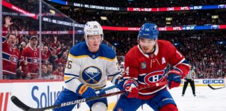 An intense moment on the ice during the Buffalo Sabres and Montreal Canadiens Game 6 matchup as Sabres defenseman Rasmus Dahlin (#26) and Canadiens captain Nick Suzuki (#14) battle fiercely for the puck at Centre Bell.