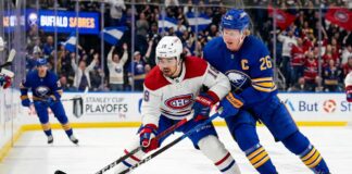 Montreal Canadiens Alex Newhook (18) and Buffalo Sabres Rasmus Dahlin (26) battle for a puck in Game 7.
