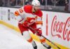 Calgary Flames Offseason Rebuild: Who Stays and Who Goes? Calgary Flames alternate captain Jonathan Huberdeau skating along the boards with the puck during an NHL game, next to a Coca-Cola advertisement.