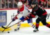 How to Watch Montreal Canadiens vs Carolina Hurricanes Game 2 on TV Today A dynamic action photograph from the 2026 NHL Eastern Conference Finals Game 1, capturing Montreal Canadiens forward Cole Caufield fighting off Carolina Hurricanes forward Taylor Hall for possession of the hockey puck during intense, physical board play at Lenovo Center.