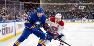 Tage Thompson #72 of the Buffalo Sabres and Nick Suzuki #14 of the Montreal Canadiens intensely battle for the puck on the ice during an NHL playoff game.