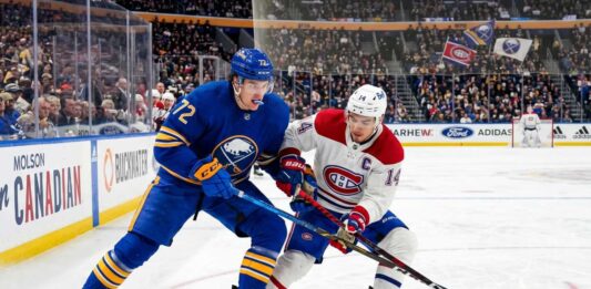 Tage Thompson #72 of the Buffalo Sabres and Nick Suzuki #14 of the Montreal Canadiens intensely battle for the puck on the ice during an NHL playoff game.