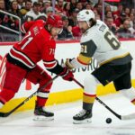 Carolina Hurricanes forward Taylor Hall takes a face-off against Vegas Golden Knights captain Mark Stone during the Stanley Cup Final, with Coca-Cola and PS5 ads visible on the boards.