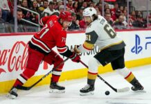 Carolina Hurricanes forward Taylor Hall takes a face-off against Vegas Golden Knights captain Mark Stone during the Stanley Cup Final, with Coca-Cola and PS5 ads visible on the boards.