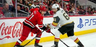 Carolina Hurricanes forward Taylor Hall takes a face-off against Vegas Golden Knights captain Mark Stone during the Stanley Cup Final, with Coca-Cola and PS5 ads visible on the boards.