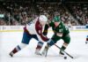 Intense puck battle between Colorado Avalanche defenseman Cale Makar (#8) and Minnesota Wild forward Kirill Kaprizov (#97) during an NHL playoff game at Xcel Energy Center.