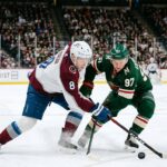 Intense puck battle between Colorado Avalanche defenseman Cale Makar (#8) and Minnesota Wild forward Kirill Kaprizov (#97) during an NHL playoff game at Xcel Energy Center.
