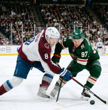 Intense puck battle between Colorado Avalanche defenseman Cale Makar (#8) and Minnesota Wild forward Kirill Kaprizov (#97) during an NHL playoff game at Xcel Energy Center.
