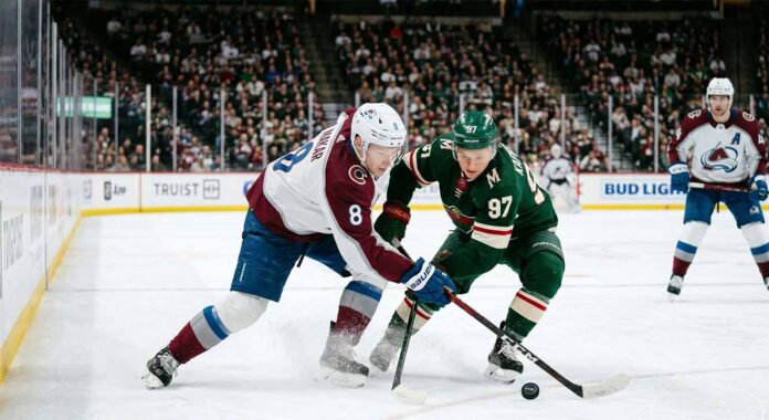 Intense puck battle between Colorado Avalanche defenseman Cale Makar (#8) and Minnesota Wild forward Kirill Kaprizov (#97) during an NHL playoff game at Xcel Energy Center.