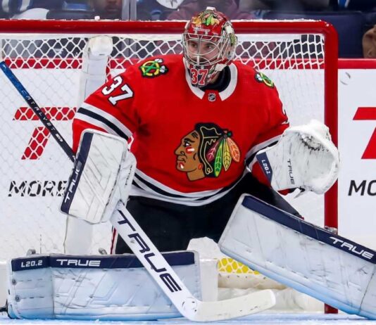 Chicago Blackhawks Trade Rumors: Connor Hellebuyck & Winnipeg Jets A photorealistic image showing goalie Connor Hellebuyck in a red Chicago Blackhawks home uniform and custom Blackhawks mask in the goal crease, illustrating potential trade rumors from the Winnipeg Jets.